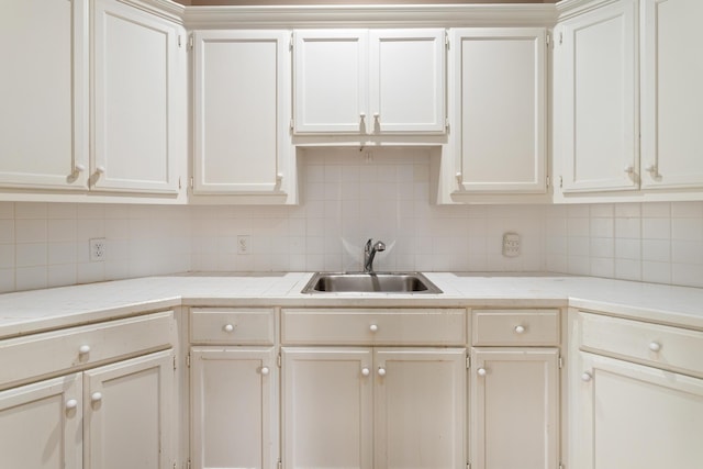 kitchen featuring white cabinets, backsplash, and sink