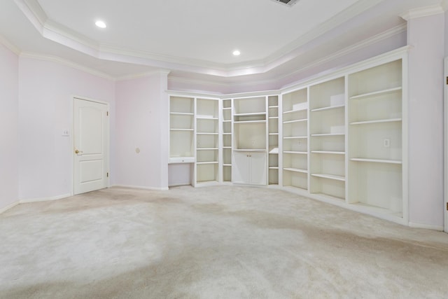 unfurnished room with built in shelves, carpet floors, a raised ceiling, and ornamental molding