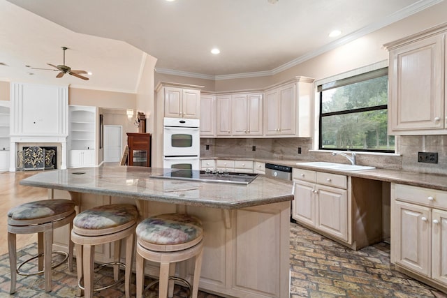 kitchen with light stone countertops, appliances with stainless steel finishes, a breakfast bar, sink, and a center island