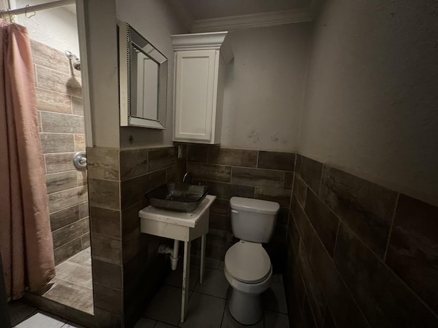 5333 Lakeside Dr, Port Arthur, TX 77642 - bathroom with a tile shower, ornamental molding, tile walls, a wainscoted wall, and tile patterned flooring