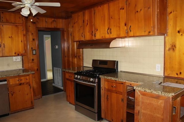 4246 Griffing Dr, Port Arthur, TX 77642 - kitchen featuring appliances with stainless steel finishes, under cabinet range hood, brown cabinets, tasteful backsplash, and wooden walls