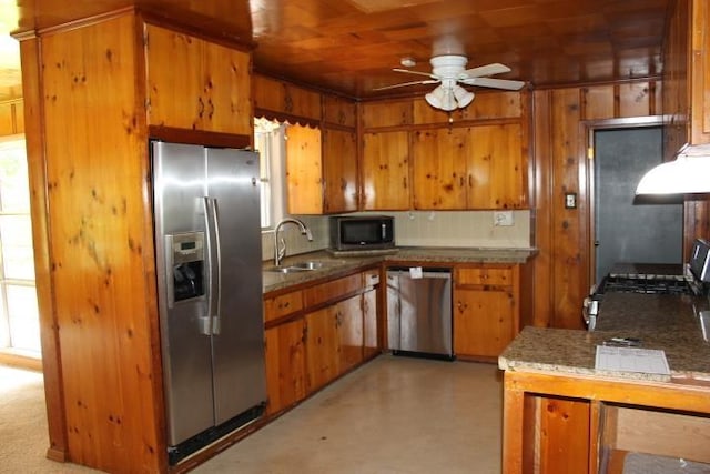 4246 Griffing Dr, Port Arthur, TX 77642 - kitchen with appliances with stainless steel finishes, a sink, ceiling fan, brown cabinets, and wooden walls