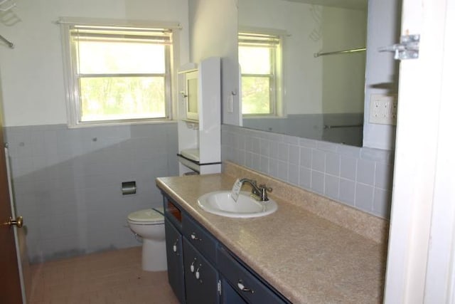 4246 Griffing Dr, Port Arthur, TX 77642 - bathroom with toilet, tile walls, vanity, and a wainscoted wall