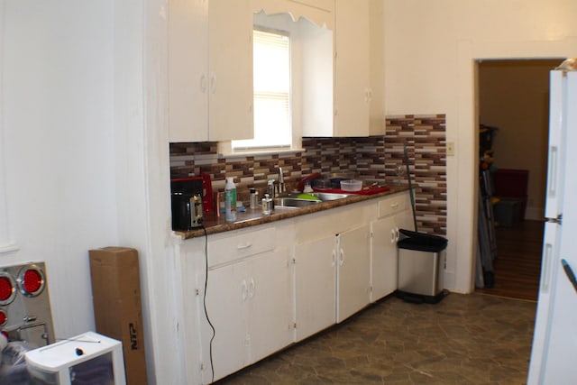 3575 Magnolia Ave, Beaumont, TX 77703 - kitchen featuring white cabinets, tasteful backsplash, dark stone finish flooring, freestanding refrigerator, and dark countertops