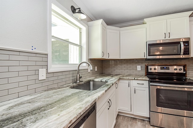 kitchen with tasteful backsplash, white cabinets, sink, and stainless steel appliances