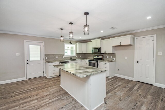 kitchen featuring white cabinetry, stainless steel appliances, decorative light fixtures, a kitchen island, and sink