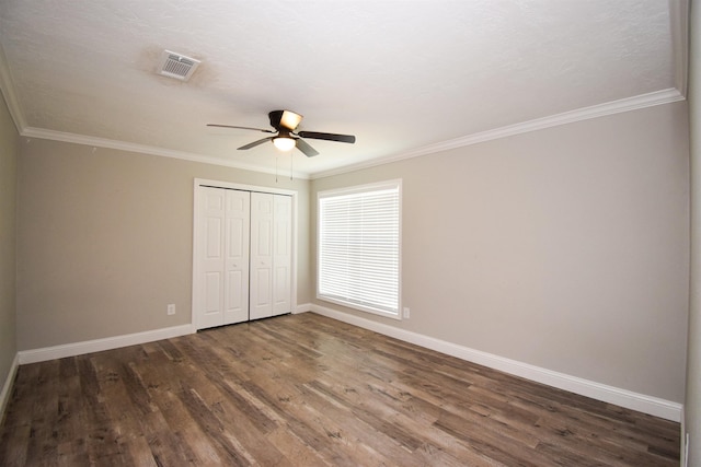 unfurnished bedroom featuring ceiling fan, ornamental molding, a closet, and dark hardwood / wood-style floors