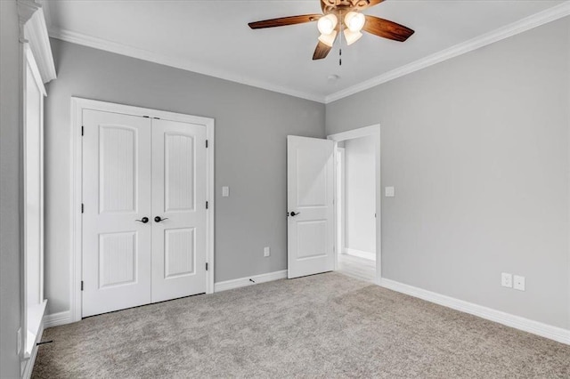 unfurnished bedroom with crown molding, ceiling fan, baseboards, carpet, and a closet