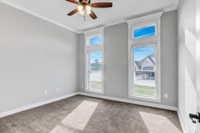 empty room featuring a healthy amount of sunlight, baseboards, crown molding, and carpet