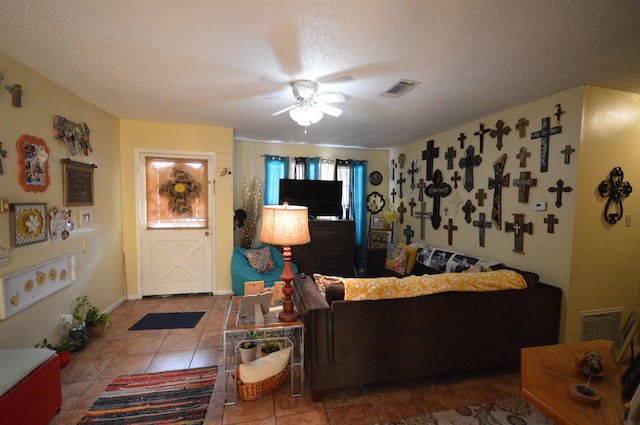 living room with tile patterned flooring, ceiling fan, and a textured ceiling