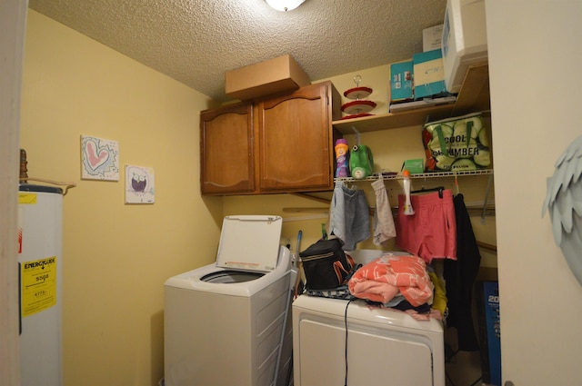 clothes washing area featuring a textured ceiling, washer and clothes dryer, cabinets, and gas water heater