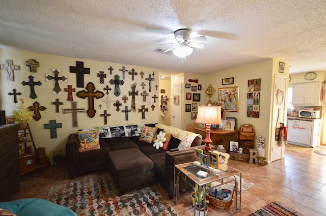 living room featuring ceiling fan, light tile patterned floors, and a textured ceiling