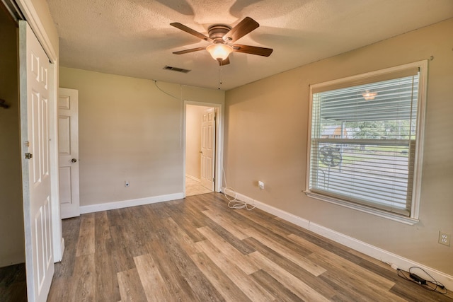 empty room featuring ceiling fan, a textured ceiling, and hardwood / wood-style flooring