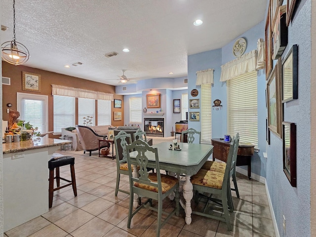 404 Pintail Ln, Orange, TX 77630 - dining space with a glass covered fireplace, ceiling fan, light tile patterned flooring, recessed lighting, and a textured ceiling