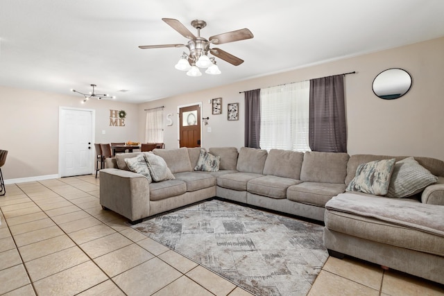 tiled living room with ceiling fan with notable chandelier