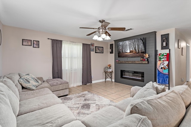 tiled living room featuring ceiling fan and a large fireplace