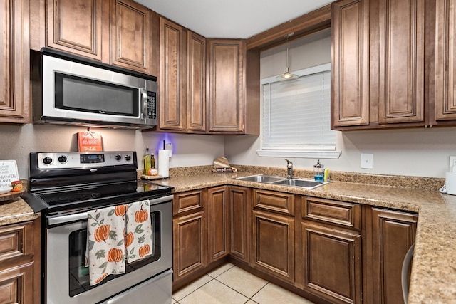 kitchen featuring light stone countertops, light tile patterned floors, stainless steel appliances, and sink