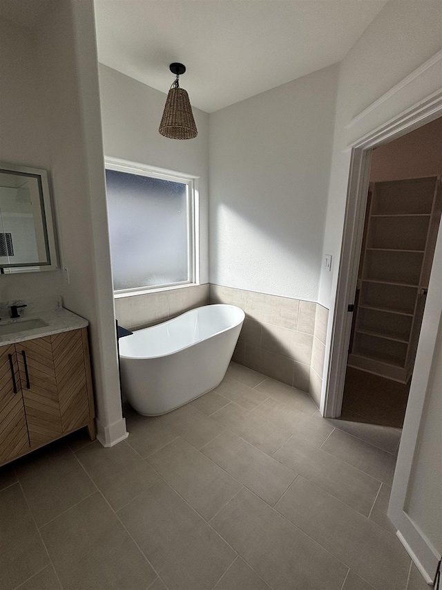 bathroom with a bathing tub, tile patterned flooring, and vanity