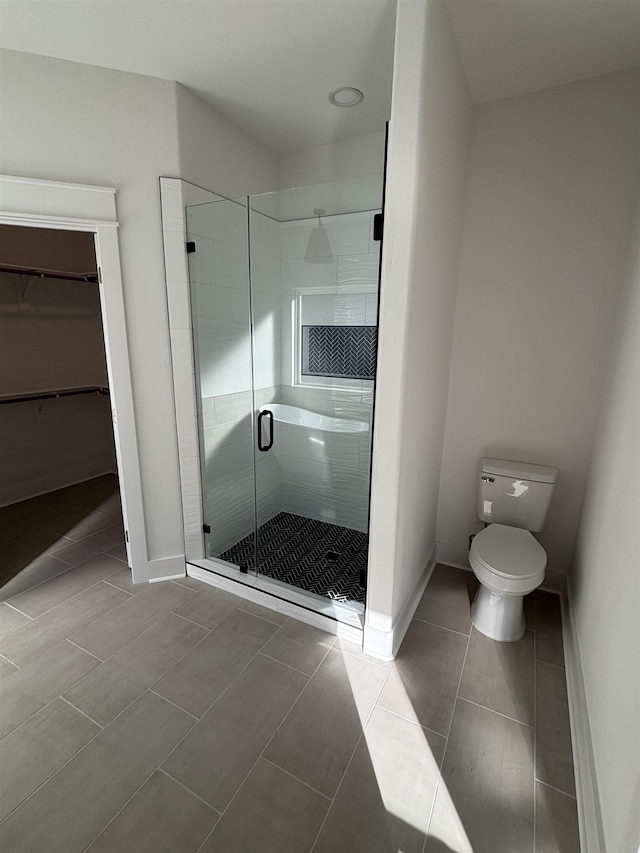 bathroom featuring toilet, tile patterned flooring, and a shower with door