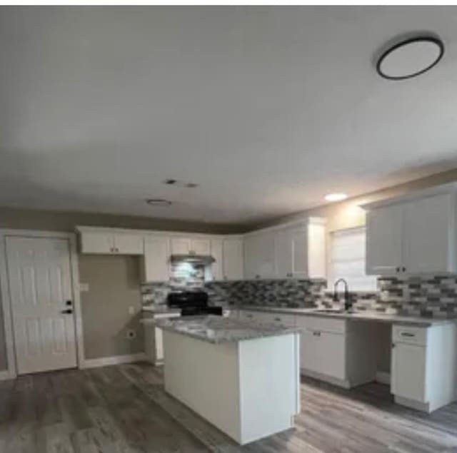 6033 Stones Throw Dr, Silsbee, TX 77656 - kitchen featuring stove, backsplash, a center island, and wood finished floors