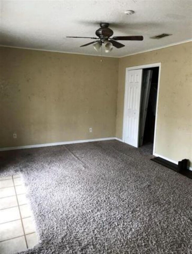 carpeted empty room with baseboards, visible vents, and ceiling fan