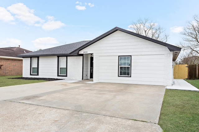 ranch-style house with brick siding, roof with shingles, and a front yard