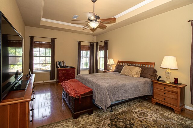 bedroom featuring a tray ceiling, ceiling fan, dark wood-type flooring, and ornamental molding