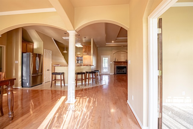 hall featuring decorative columns, light hardwood / wood-style floors, and ornamental molding