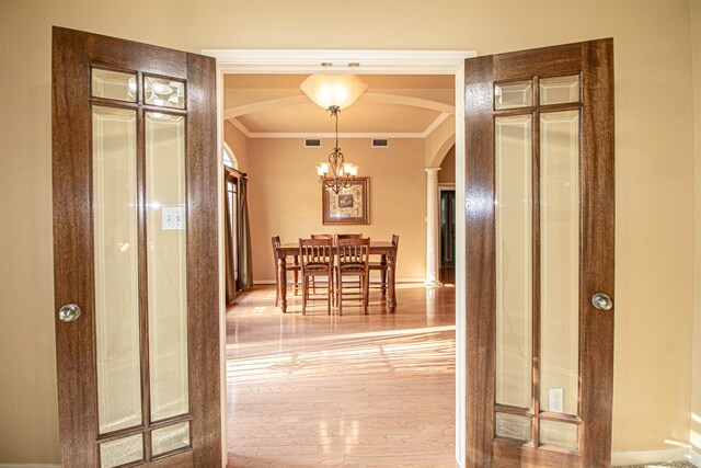 corridor with crown molding, hardwood / wood-style floors, and a chandelier