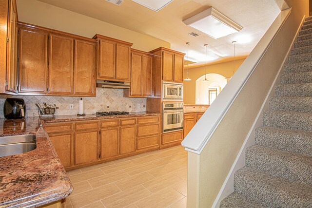 kitchen with tasteful backsplash, pendant lighting, stainless steel appliances, and sink