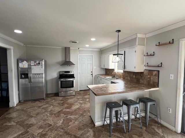 kitchen featuring pendant lighting, wall chimney exhaust hood, white cabinetry, kitchen peninsula, and stainless steel appliances