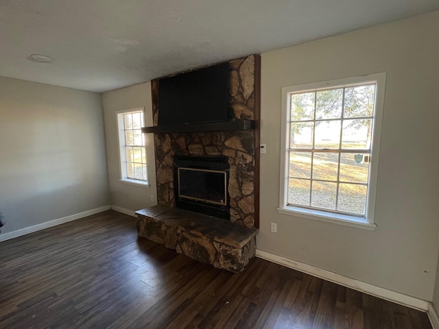 living room featuring a stone fireplace and dark hardwood / wood-style flooring