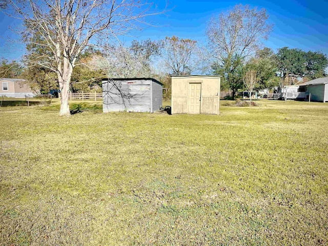 view of yard with a storage shed, an outdoor structure, and fence