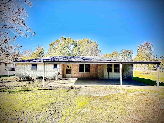 rear view of property featuring brick siding, a patio area, and a lawn