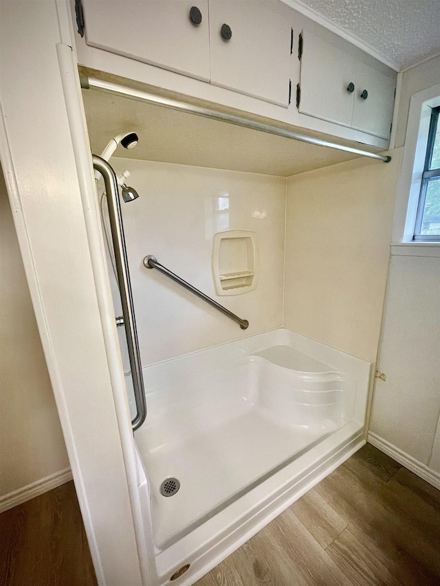 bathroom featuring wood finished floors, a shower, and baseboards