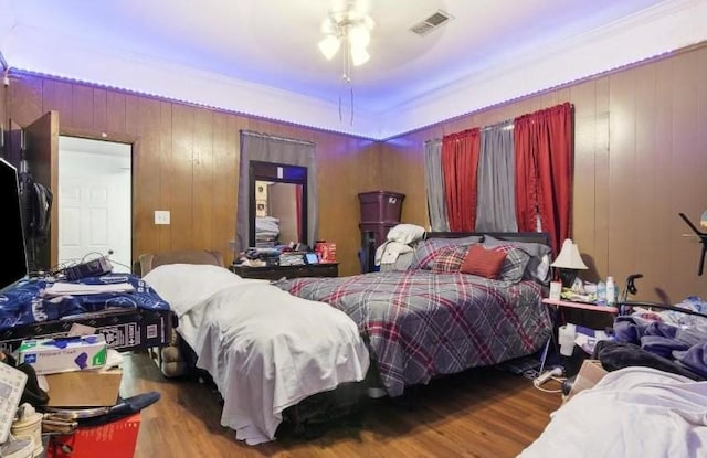 bedroom featuring ceiling fan, wooden walls, and hardwood / wood-style flooring