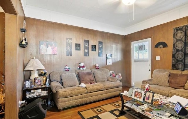 living room featuring ceiling fan, wood walls, and light hardwood / wood-style floors