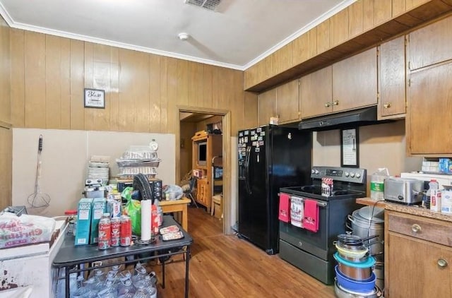 kitchen with black appliances, wood walls, light wood-type flooring, and crown molding