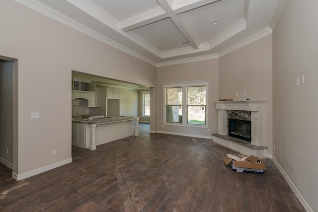 unfurnished living room featuring coffered ceiling, dark wood-type flooring, crown molding, beamed ceiling, and a fireplace