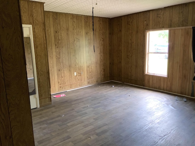 unfurnished room featuring dark hardwood / wood-style flooring and wooden walls