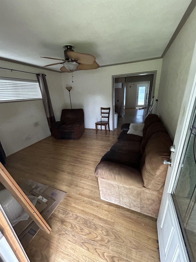 living room with ceiling fan, a textured ceiling, and light wood-type flooring