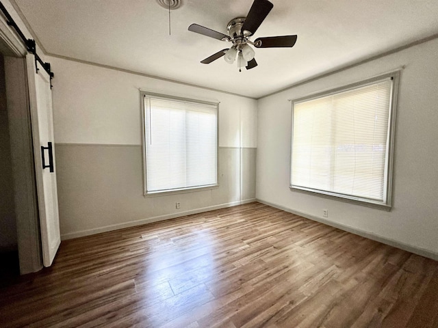 312 Temple, Woodville, TX 75979 - spare room featuring wood finished floors, a ceiling fan, and a barn door