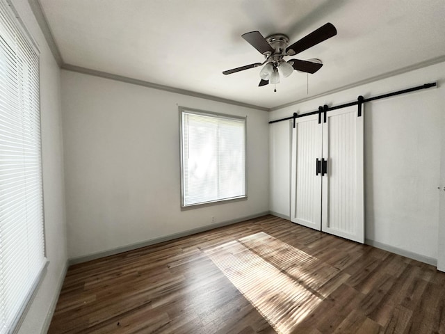 312 Temple, Woodville, TX 75979 - unfurnished bedroom with a barn door, wood finished floors, crown molding, and a ceiling fan