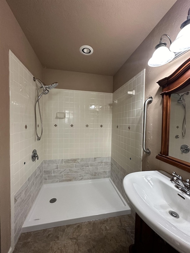 bathroom with a tile shower and vanity