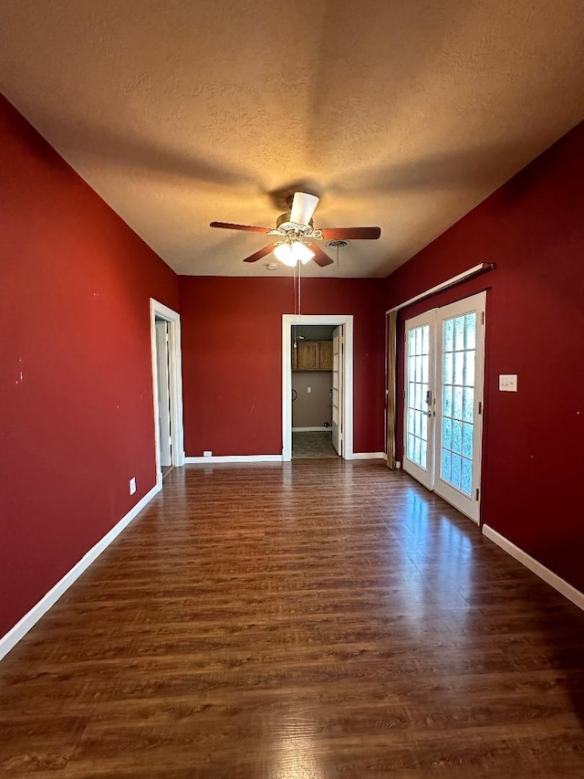 unfurnished room with a textured ceiling, ceiling fan, dark wood-type flooring, and french doors