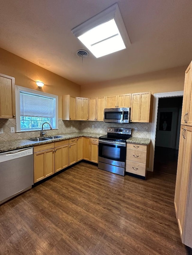 kitchen with light stone countertops, appliances with stainless steel finishes, sink, light brown cabinets, and dark hardwood / wood-style floors