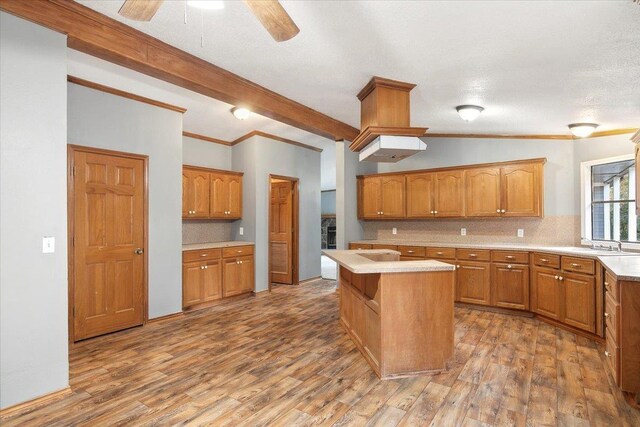 kitchen with decorative backsplash, vaulted ceiling with beams, dark hardwood / wood-style flooring, crown molding, and a center island