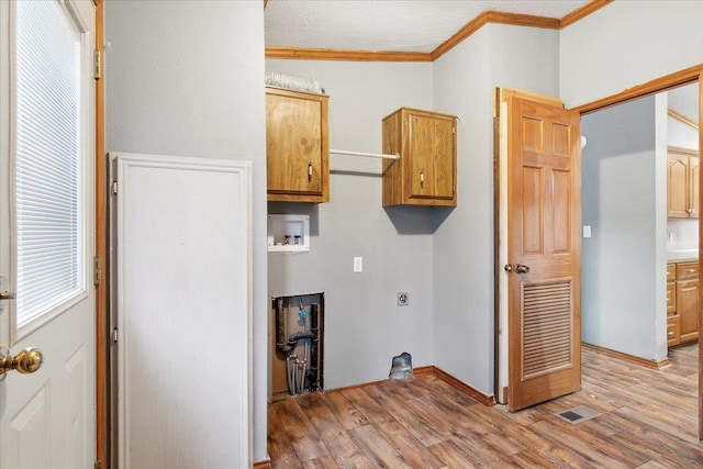 laundry room featuring cabinets, hookup for an electric dryer, crown molding, hookup for a washing machine, and light wood-type flooring