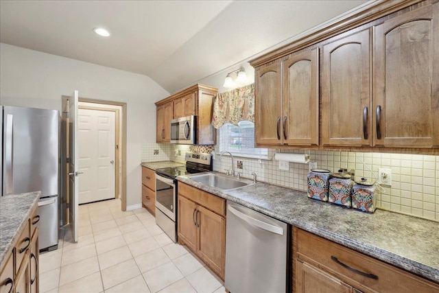 7385 Hidden Valley Dr, Beaumont, TX 77706 - kitchen with appliances with stainless steel finishes, a sink, lofted ceiling, light tile patterned flooring, and tasteful backsplash