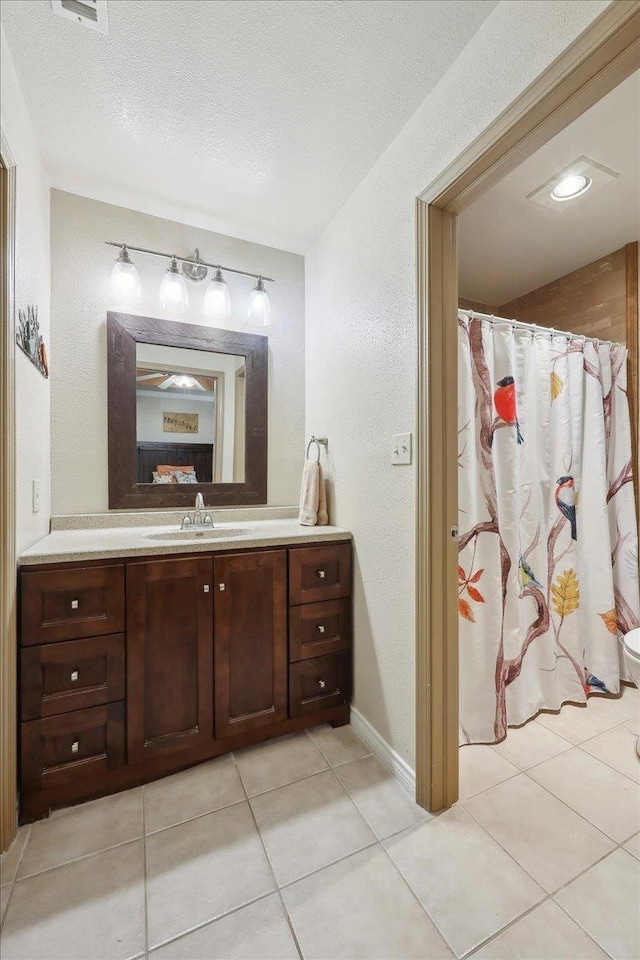 7385 Hidden Valley Dr, Beaumont, TX 77706 - full bathroom with vanity, tile patterned floors, a textured wall, a textured ceiling, and baseboards